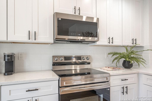 kitchen featuring light stone countertops, tasteful backsplash, white cabinetry, and stainless steel appliances