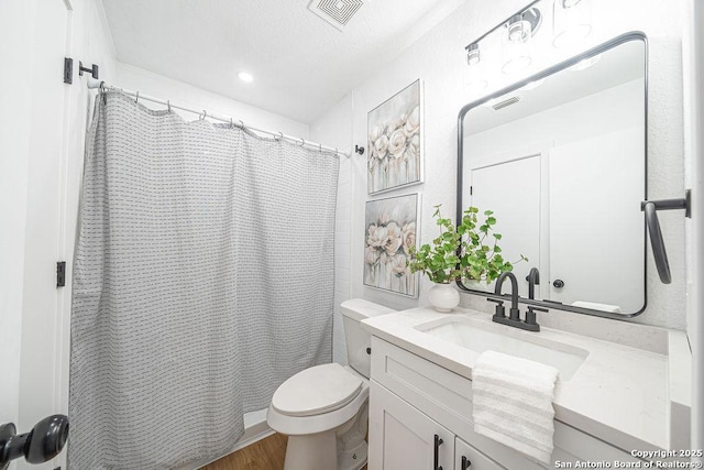 full bath with visible vents, vanity, toilet, and wood finished floors