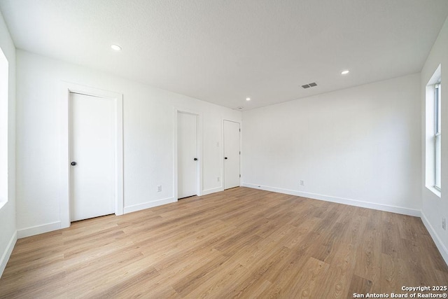 empty room featuring recessed lighting, baseboards, visible vents, and light wood finished floors