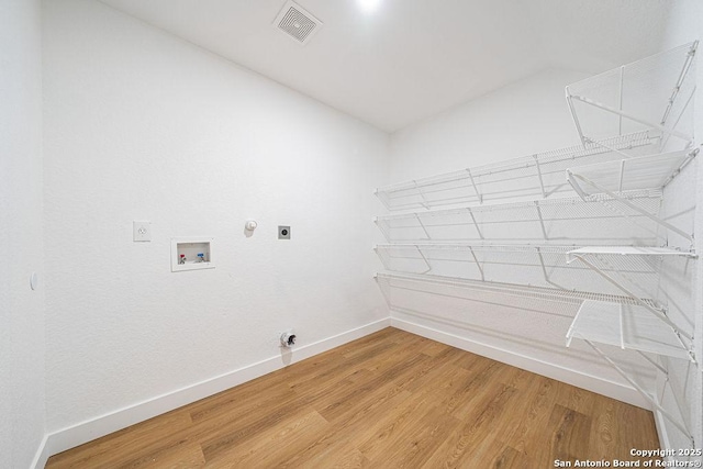 washroom with hookup for a washing machine, hookup for an electric dryer, laundry area, visible vents, and light wood-type flooring