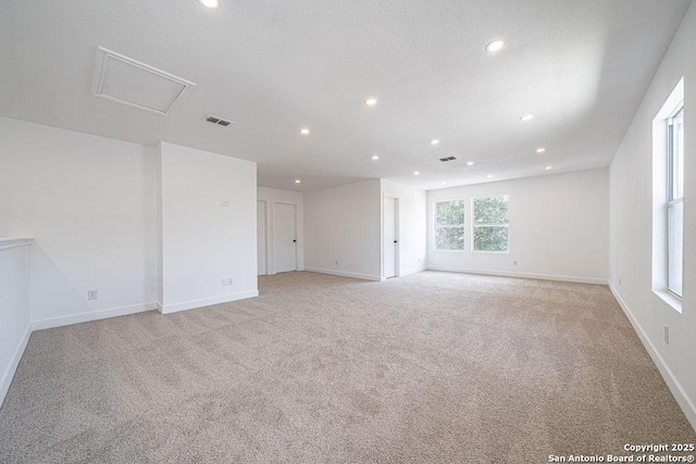 empty room featuring carpet, a textured ceiling, baseboards, and recessed lighting