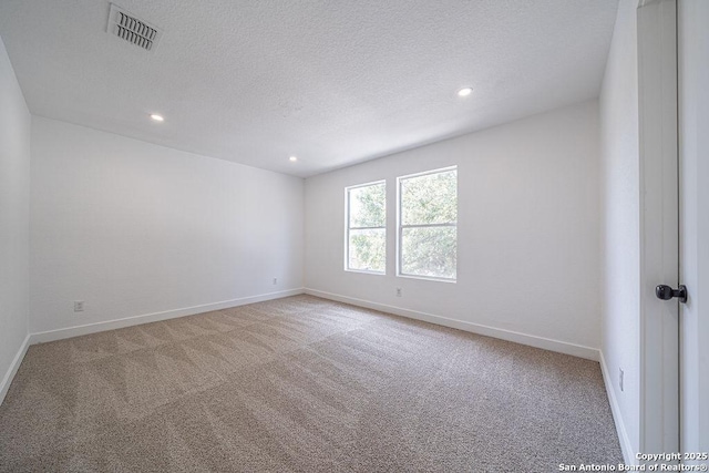 unfurnished room with a textured ceiling, recessed lighting, carpet floors, visible vents, and baseboards