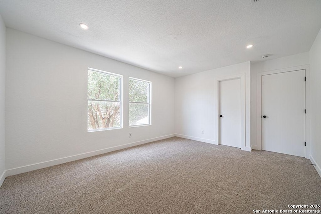 empty room with carpet, baseboards, a textured ceiling, and recessed lighting