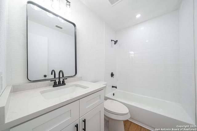 bathroom featuring shower / bathtub combination, toilet, wood finished floors, vanity, and visible vents