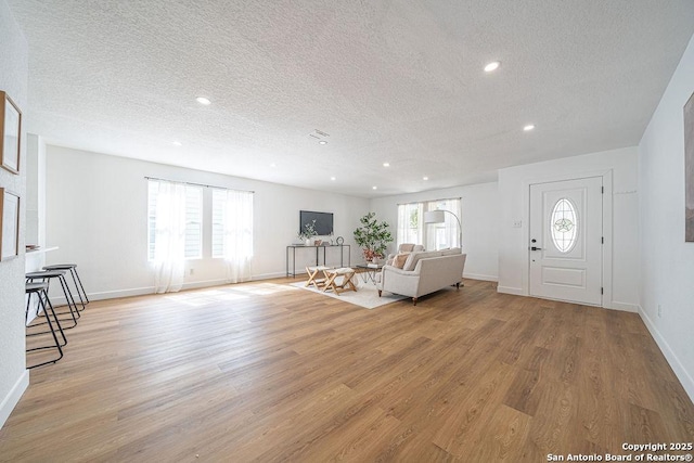 unfurnished living room with baseboards, a textured ceiling, light wood-type flooring, and recessed lighting