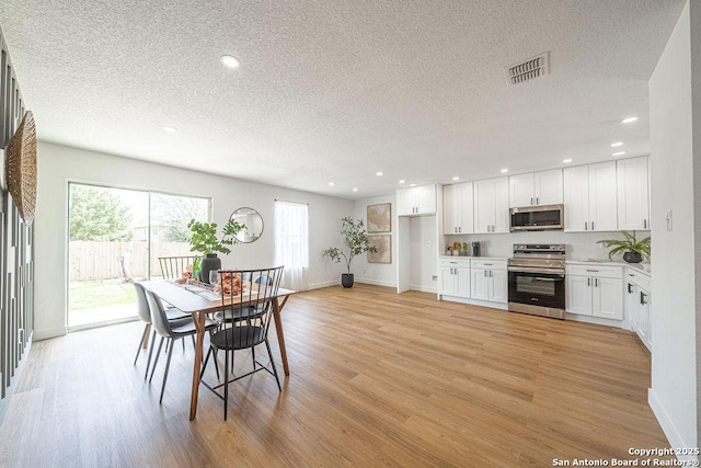 dining room featuring a textured ceiling, recessed lighting, visible vents, and light wood-style floors