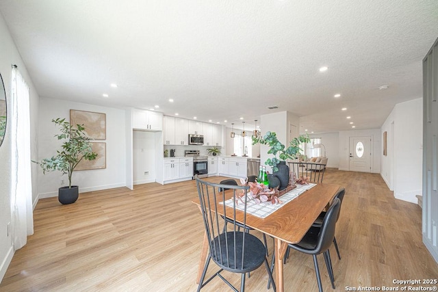 dining space with a textured ceiling, light wood-type flooring, and recessed lighting