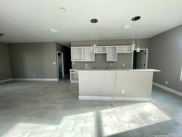 kitchen featuring baseboards, white cabinets, hanging light fixtures, light countertops, and a center island