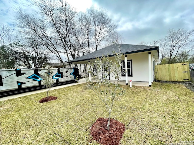 view of front of home with a front yard, fence, and stucco siding