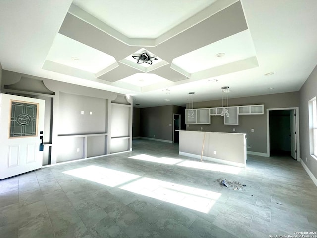 unfurnished living room featuring a tray ceiling and baseboards