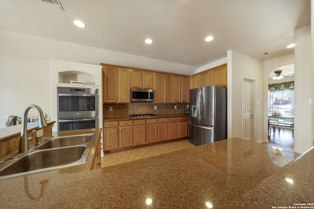 kitchen featuring light tile patterned flooring, a sink, visible vents, appliances with stainless steel finishes, and decorative backsplash