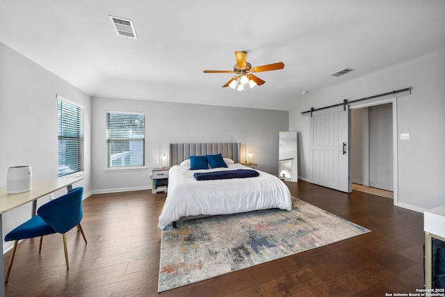 bedroom with wood finished floors, visible vents, and a barn door