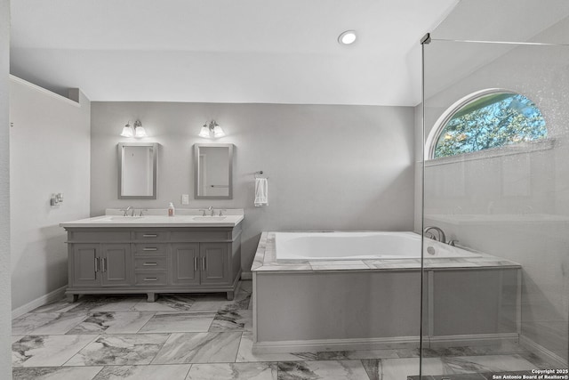 bathroom featuring a garden tub, marble finish floor, double vanity, and a sink