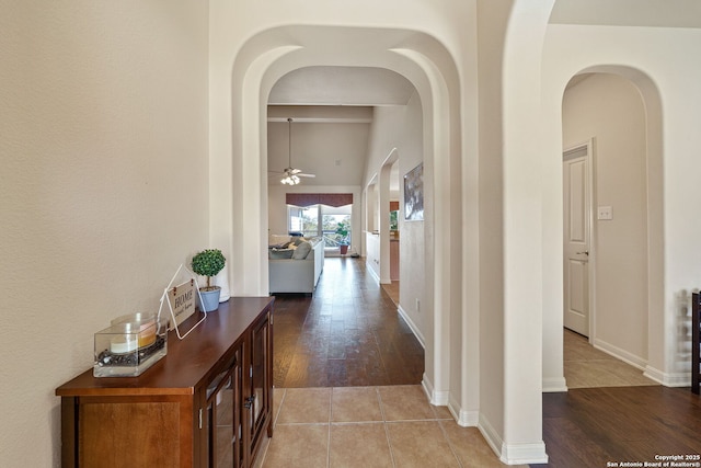 hall with light tile patterned floors, baseboards, and arched walkways