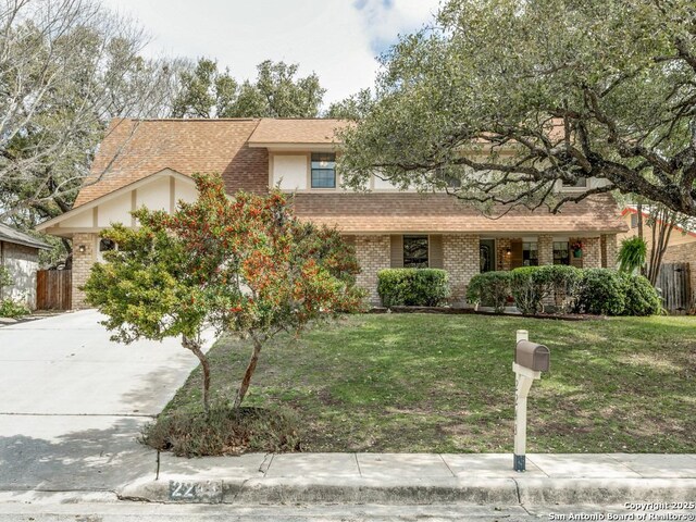 view of front of home with a garage, roof with shingles, brick siding, and a front lawn