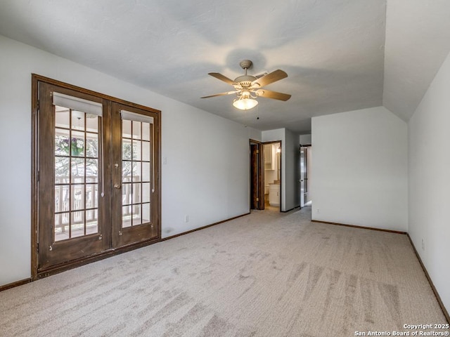 empty room featuring ceiling fan, light carpet, baseboards, vaulted ceiling, and french doors