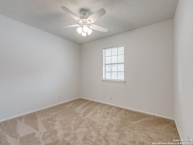 carpeted spare room with baseboards, a ceiling fan, and a textured ceiling