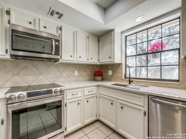 kitchen featuring a sink, visible vents, light countertops, appliances with stainless steel finishes, and decorative backsplash