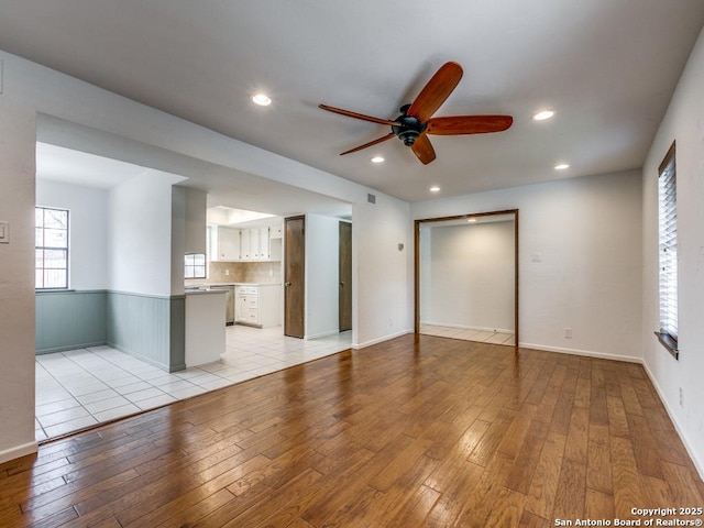 unfurnished living room featuring visible vents, a ceiling fan, wainscoting, light wood-type flooring, and recessed lighting