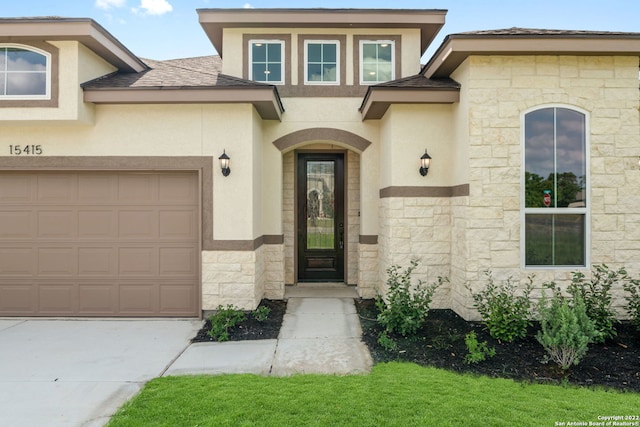 property entrance with a garage, stone siding, a shingled roof, and stucco siding