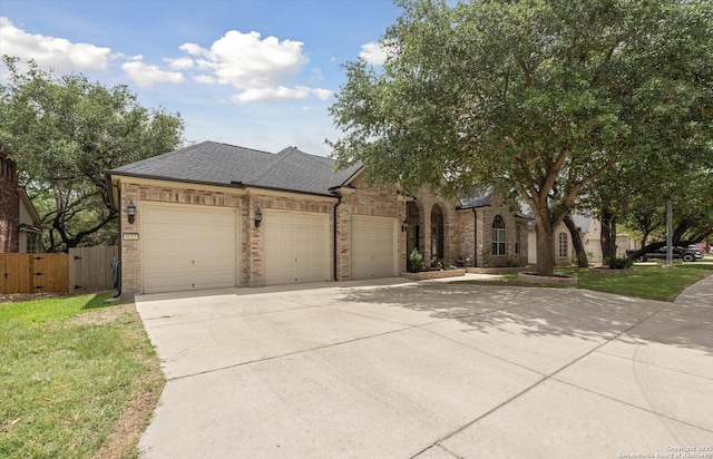 view of front of home with concrete driveway, roof with shingles, an attached garage, fence, and brick siding