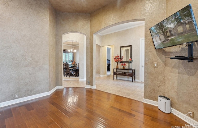 hallway featuring arched walkways, hardwood / wood-style floors, and baseboards