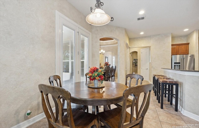 dining space with light tile patterned floors, visible vents, arched walkways, baseboards, and recessed lighting