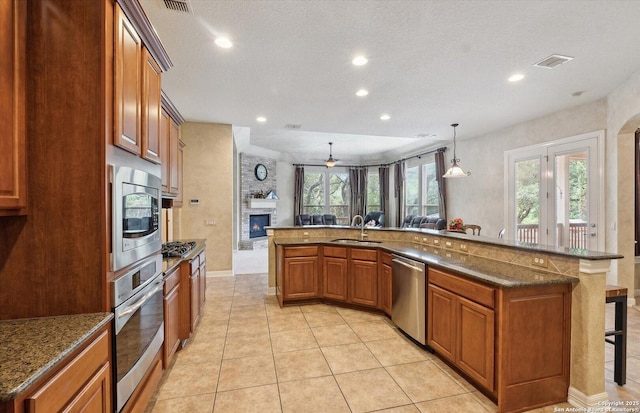 kitchen with a breakfast bar area, stainless steel appliances, a sink, visible vents, and brown cabinetry