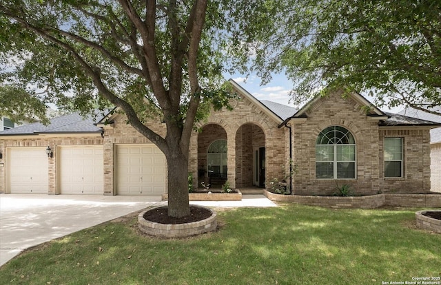 view of front of house featuring an attached garage, brick siding, driveway, roof with shingles, and a front lawn