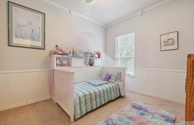 carpeted bedroom with a wainscoted wall and crown molding