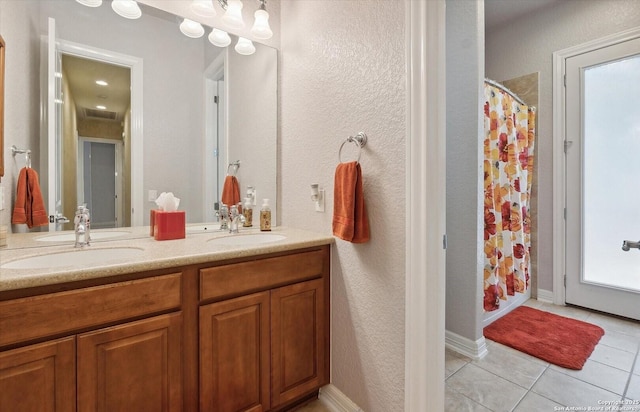 bathroom featuring double vanity, curtained shower, a sink, and tile patterned floors