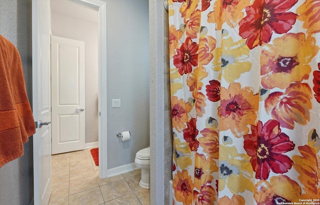 bathroom featuring baseboards, a shower with shower curtain, toilet, and tile patterned floors