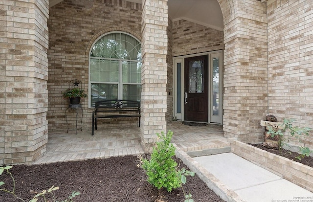 property entrance featuring covered porch and brick siding