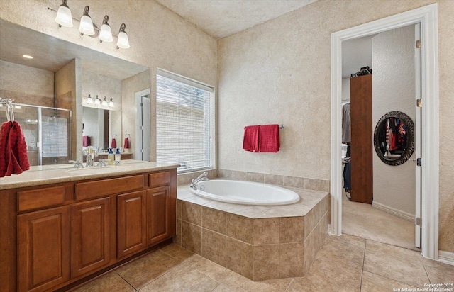 full bath with a walk in closet, tile patterned floors, vanity, a shower stall, and a bath