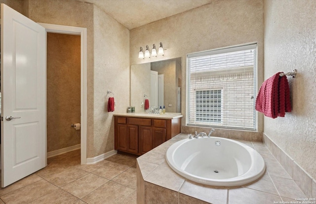 full bath featuring a textured wall, tile patterned flooring, a bath, and vanity