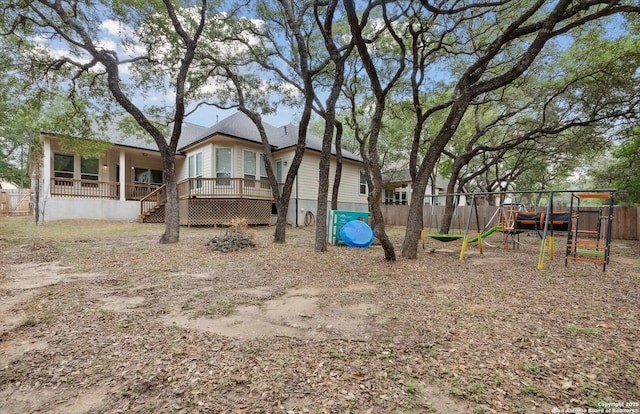 exterior space featuring a playground, fence, and a deck