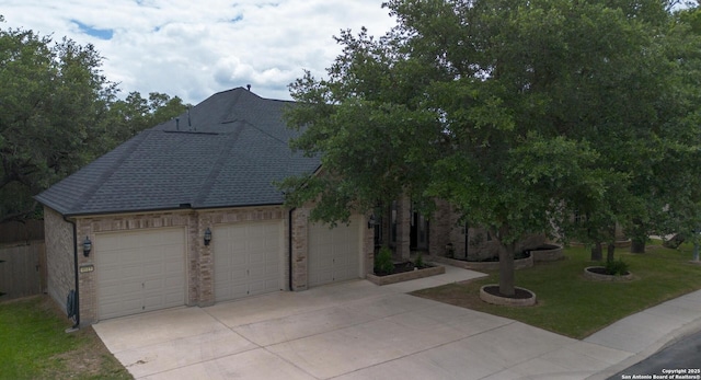 view of front of house featuring driveway, a shingled roof, an attached garage, a front lawn, and brick siding