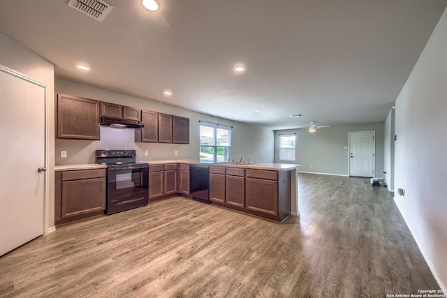 kitchen featuring light countertops, visible vents, a peninsula, under cabinet range hood, and black appliances