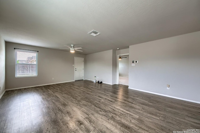 unfurnished room featuring a ceiling fan, visible vents, dark wood finished floors, and baseboards