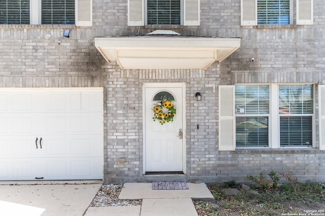 doorway to property featuring a garage and brick siding