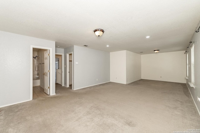 unfurnished room featuring visible vents, light carpet, a textured ceiling, and baseboards