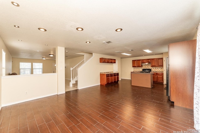 unfurnished living room featuring dark wood-type flooring, recessed lighting, and stairs