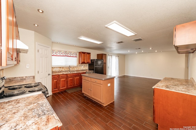 kitchen with visible vents, dark wood-style flooring, freestanding refrigerator, stainless steel range with electric cooktop, and backsplash