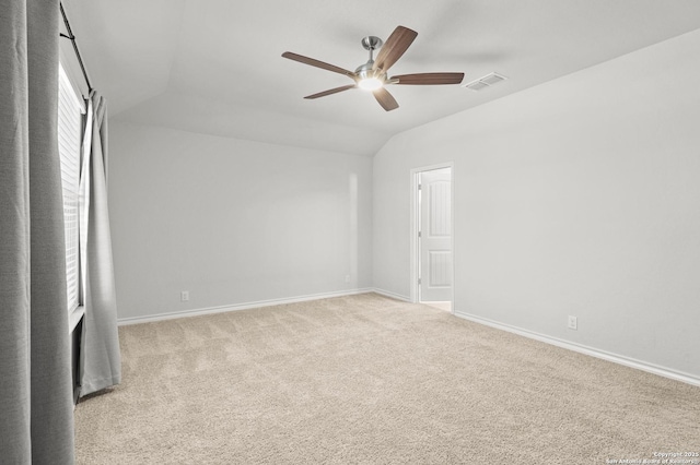 carpeted spare room with lofted ceiling, ceiling fan, visible vents, and baseboards