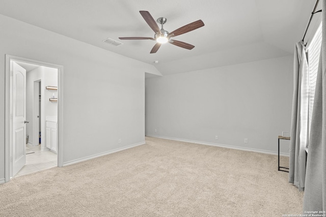 unfurnished bedroom with light carpet, a ceiling fan, visible vents, vaulted ceiling, and baseboards