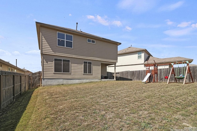 rear view of house featuring a playground, a yard, and a fenced backyard