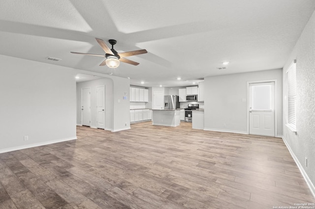 unfurnished living room featuring recessed lighting, visible vents, light wood-style flooring, a ceiling fan, and baseboards