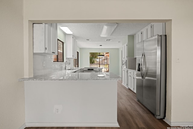 kitchen featuring stainless steel appliances, a peninsula, a sink, dark wood-style floors, and tasteful backsplash