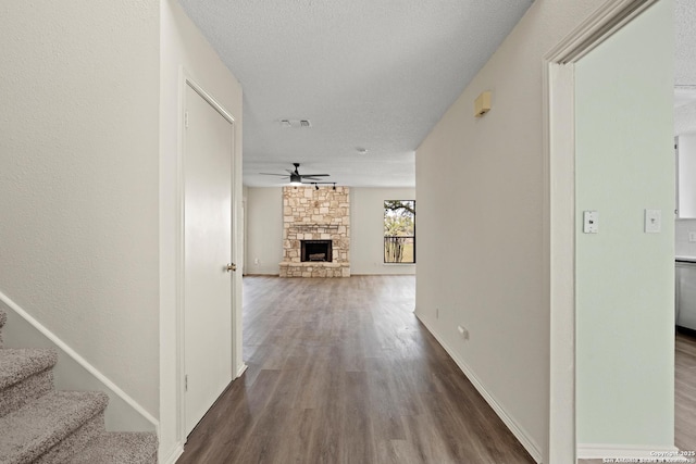 hallway with stairs, a textured ceiling, baseboards, and wood finished floors