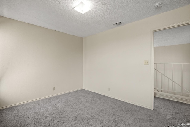 carpeted spare room with visible vents, a textured ceiling, and baseboards